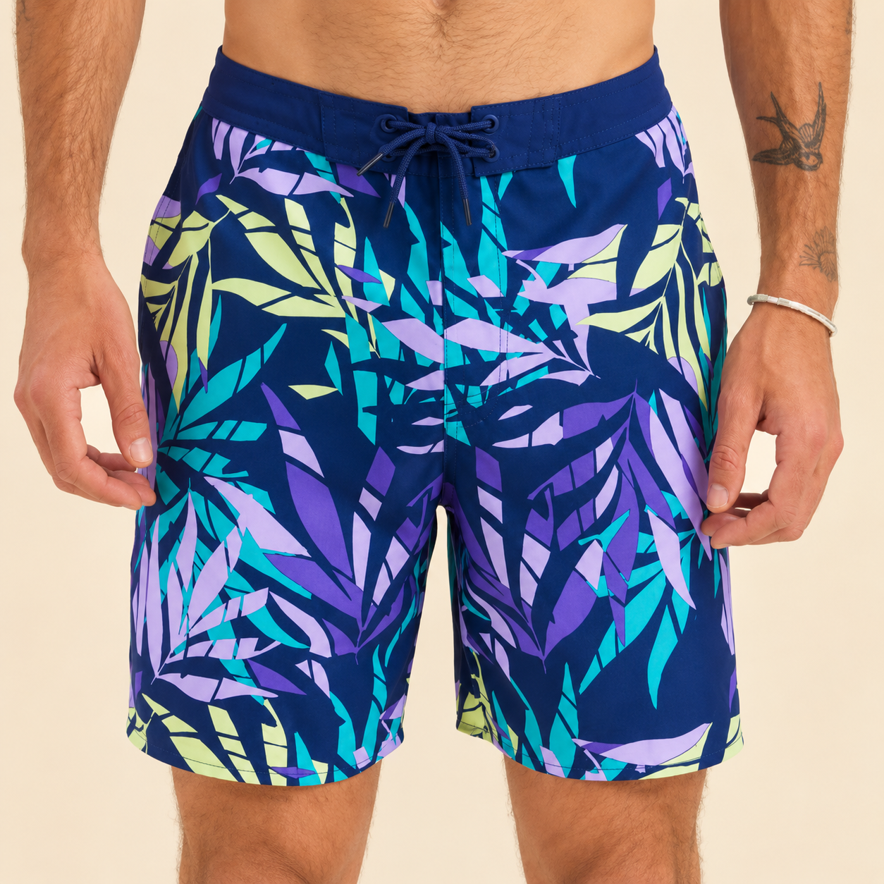 Model wearing swim trunks with a tropical leaf print in purple and teal