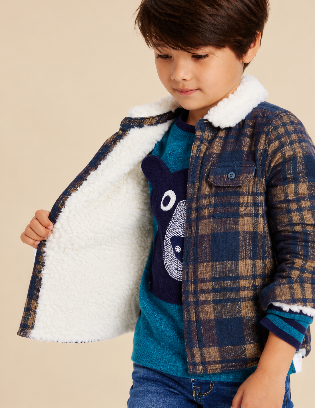 Boy wearing a navy plaid sherpa-lined shacket over a teal bear-graphic sweater