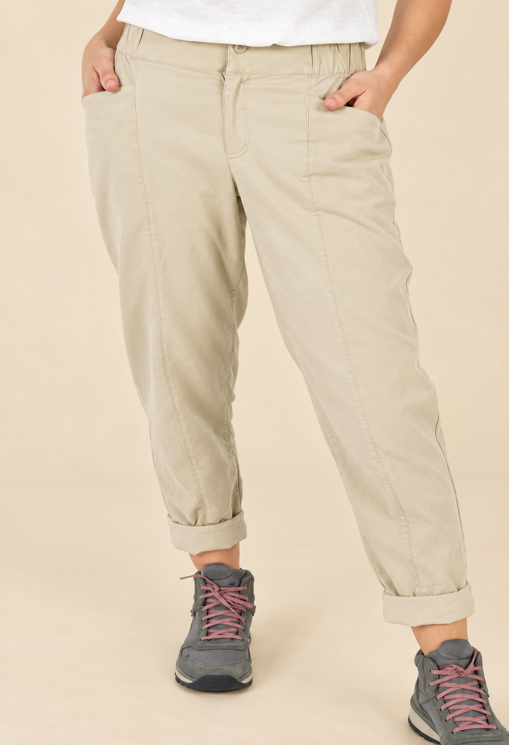 Model wearing beige cuffed trousers with grey hiking sneakers